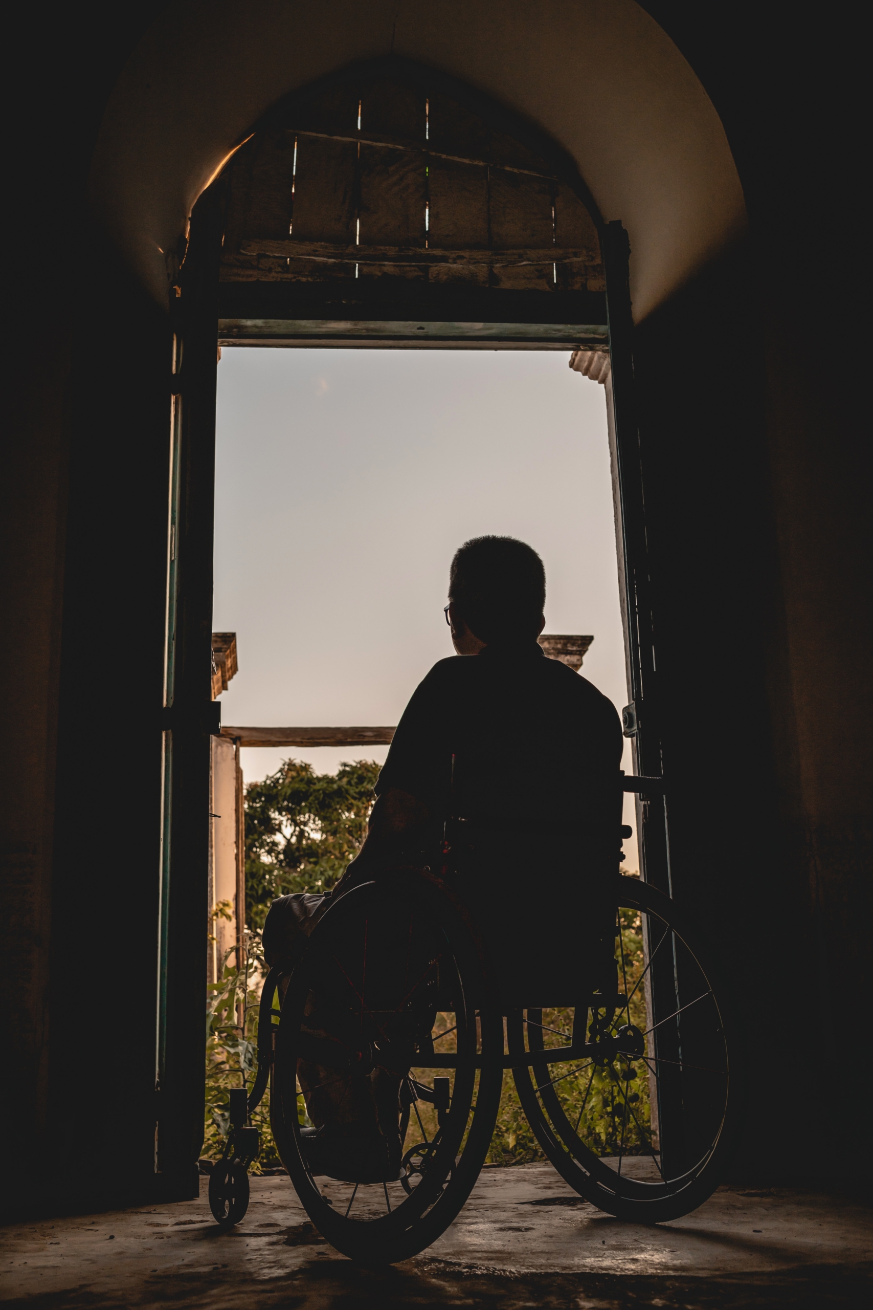 una persona en silla de ruedas se coloca a contraluz frente a una ventana.